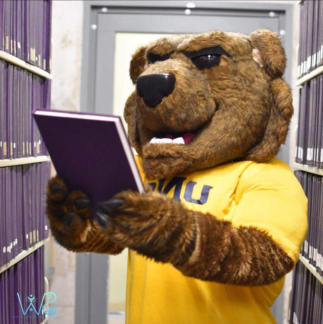 UNC mascot Klawz browsing the stacks of archived dissertations at University Libraries.